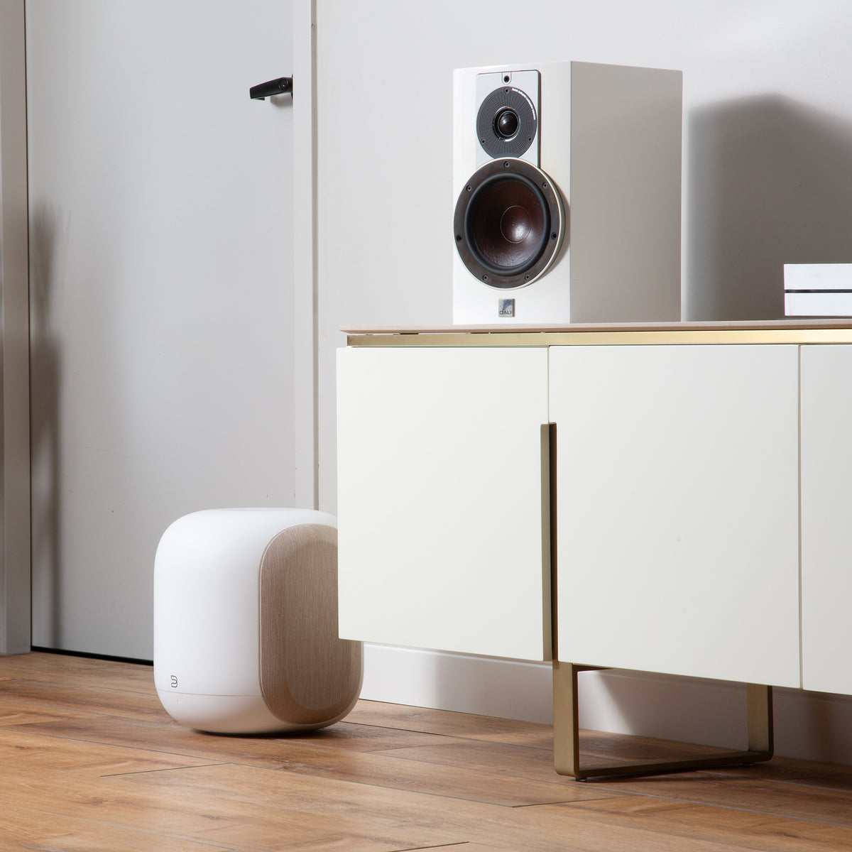 Bluesound-PULSE-SUB-White---right-with-Dali-bookshelf-and-POWERNODE-on-white-credenza-on-wood-floor.jpg?v=1787941543&width=1200